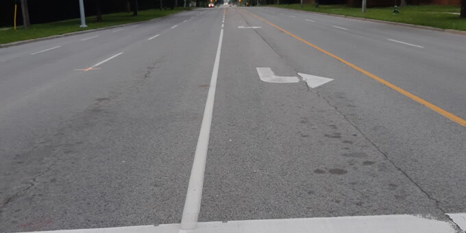 The image depicts a road with white and yellow lines in the middle as nudges